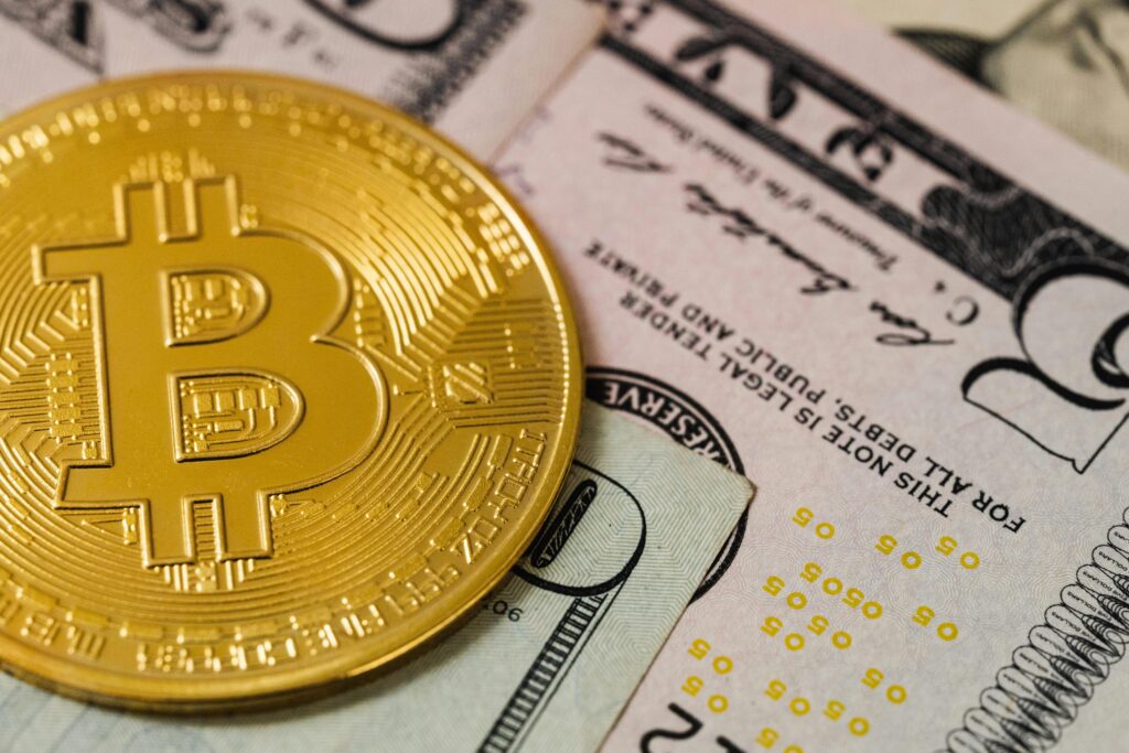 Close-up of a Bitcoin coin placed on US dollar bills, depicting cryptocurrency and traditional currency.