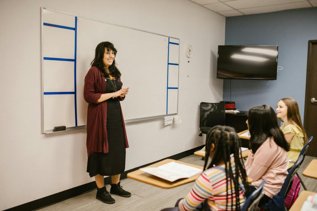 A teacher conducts a lesson with attentive diverse students in a modern classroom setting.